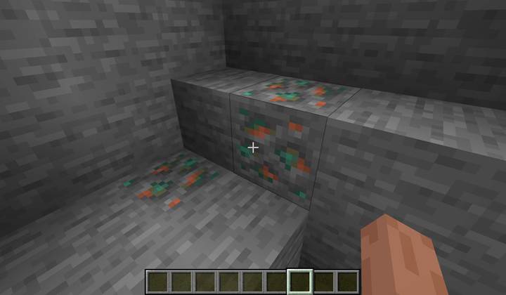 A player descends into a mid-depth cave in Minecraft, targeting the copper-rich Y47–48 band illuminated by torches.